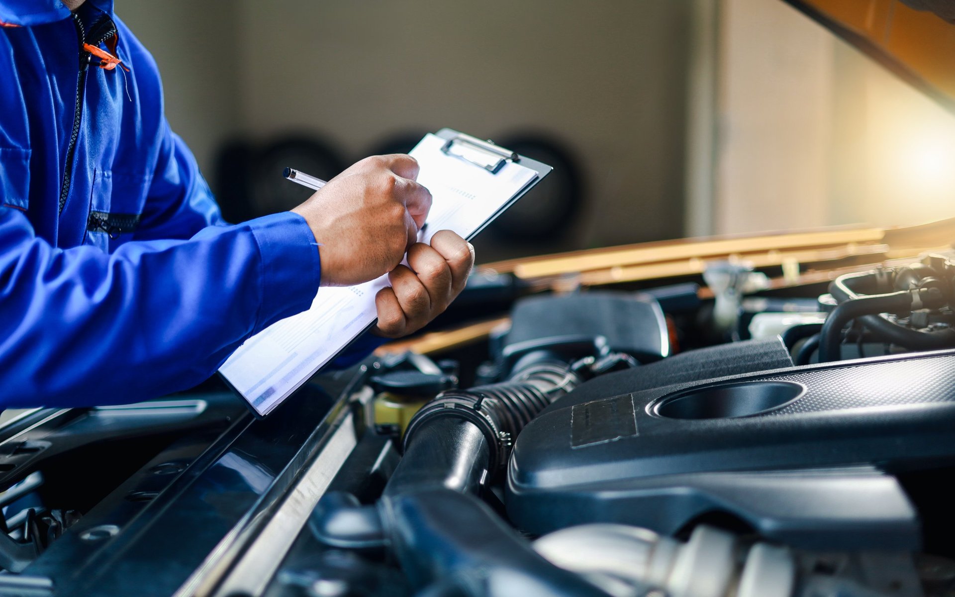 Mechanic inspecting car engine condition with clipboard, automotive vehicle inspection
