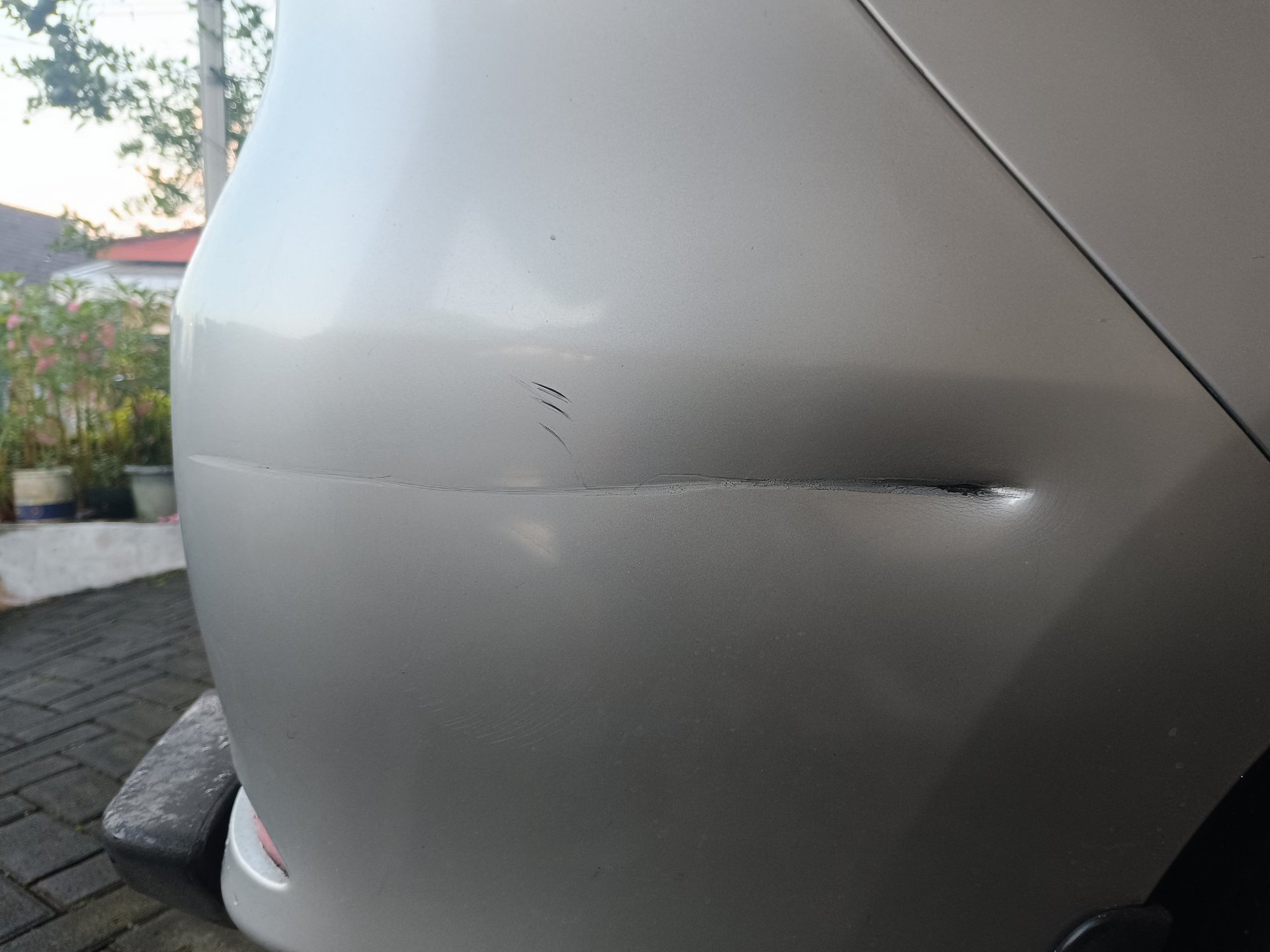 Kratzer und leichte Delle am hinteren Stoßfänger eines Autos mit Parksensor, typischer Fall an der Bagatellgrenze