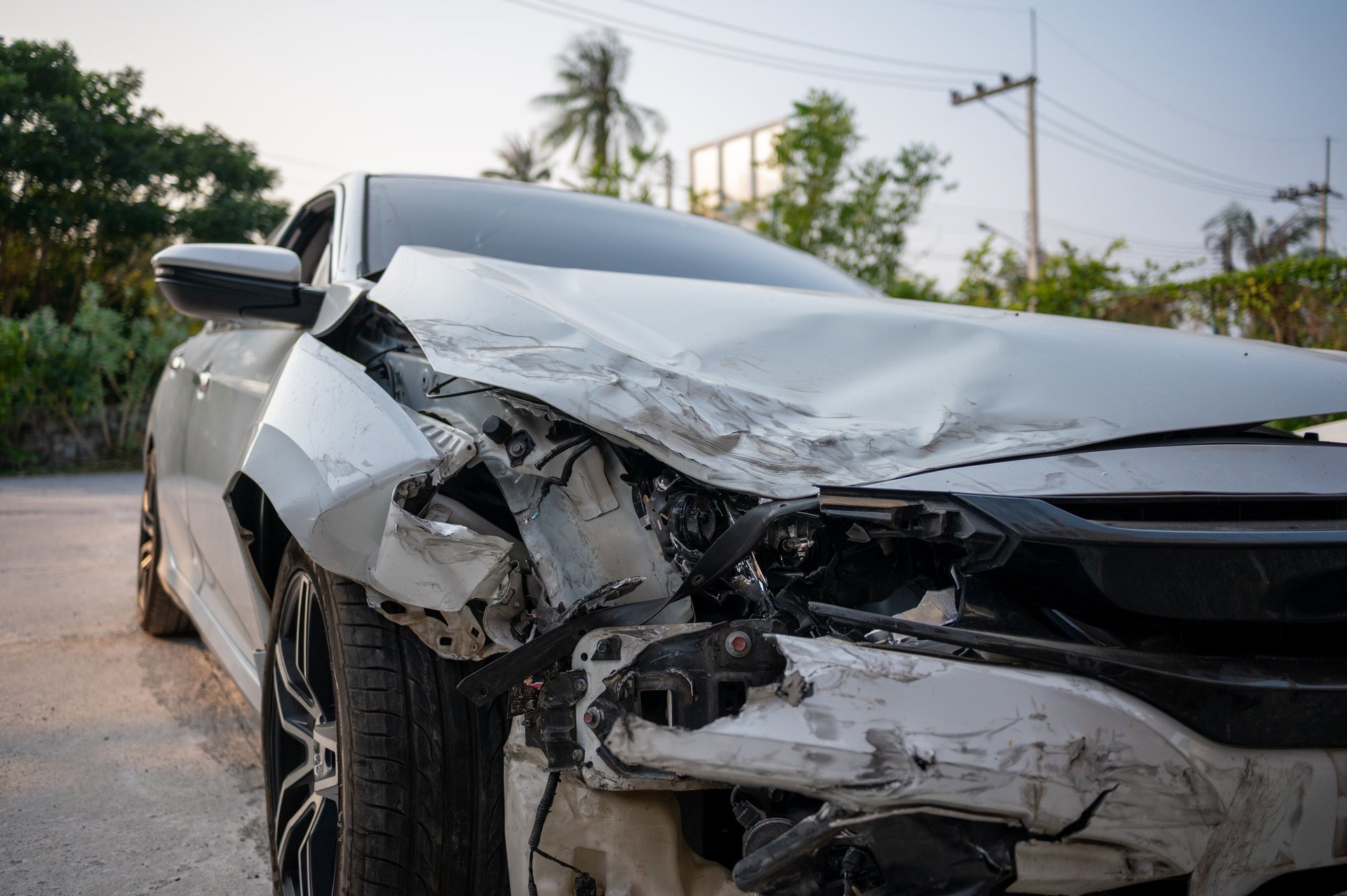 Close-up of a white car with significant front-end damage after a collision.