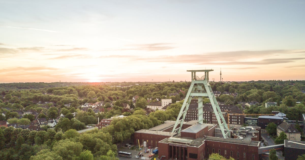 Aerial view of a coal mine headframe structure overlooking a sprawling industrial landscape at sunset