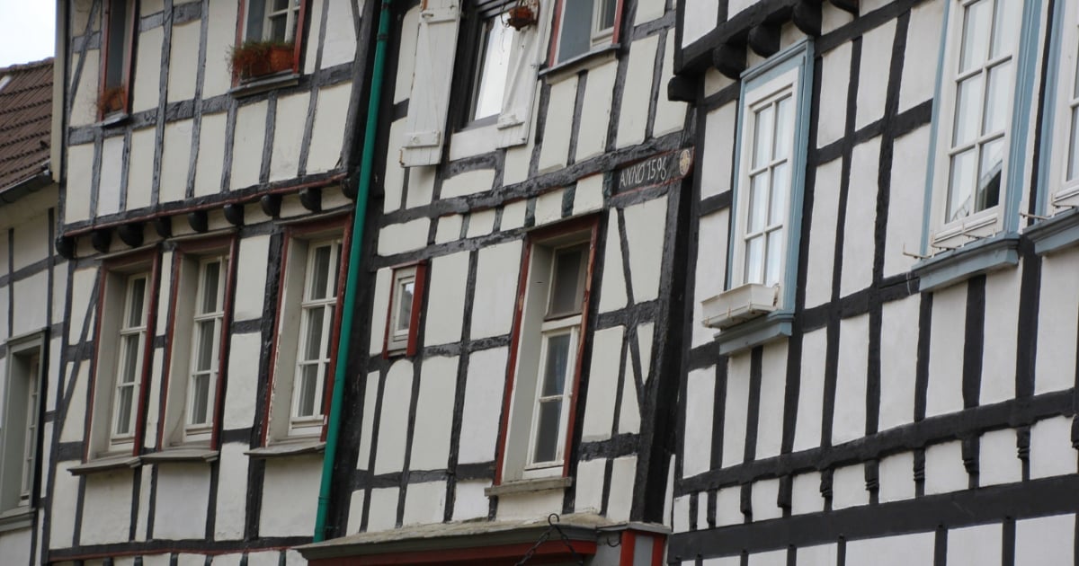 Close-up of historic half-timbered building facade with white walls, black timber framing, and multiple casement windows